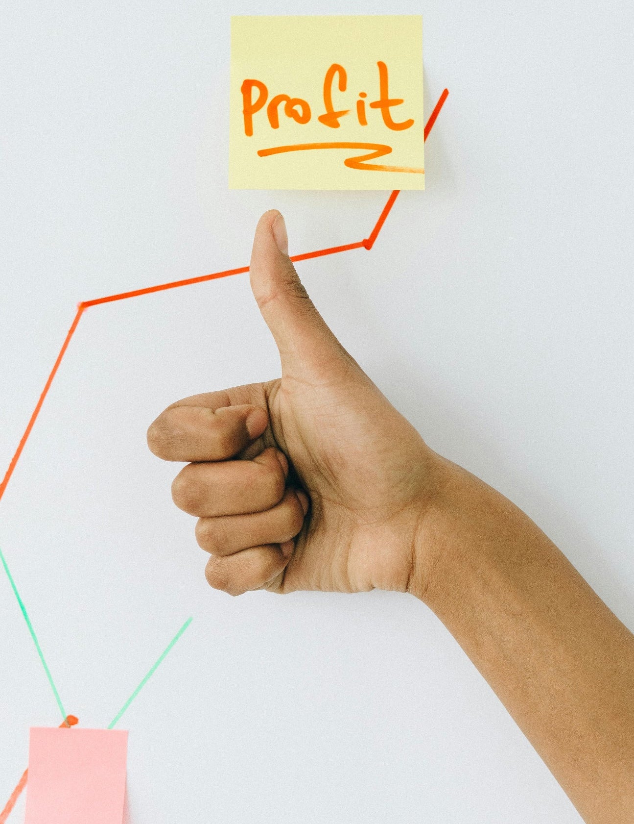 Hand giving a thumbs up next to a sticky note with 'Profit' written on it, with a graph on a white background.